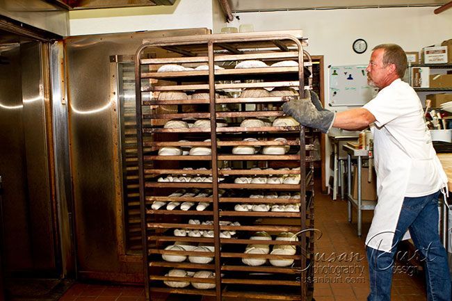 German baker Thomas Kohnen moving a tall rack of bread dough into the walk-in refrigerator
